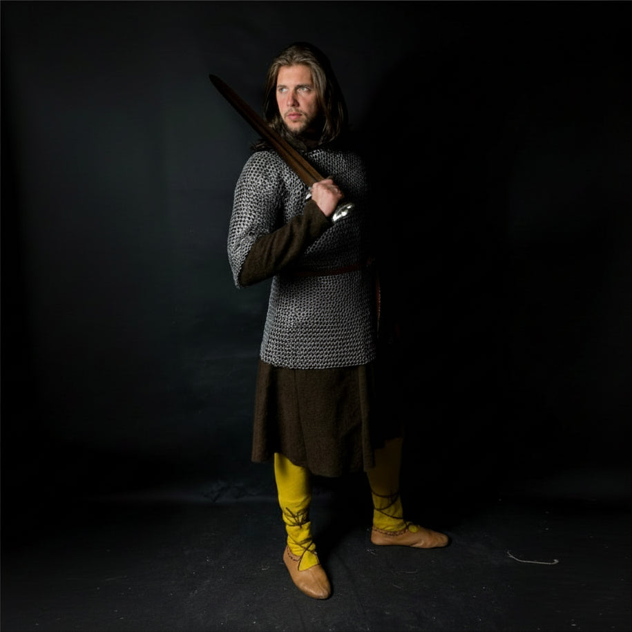 Person in medieval armor holding a sword against a black background