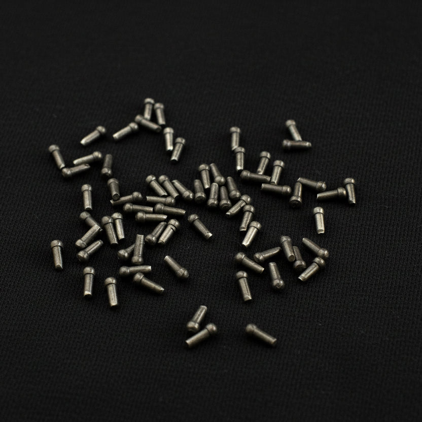 Small metal pins scattered on a white background with Rusehana logo.